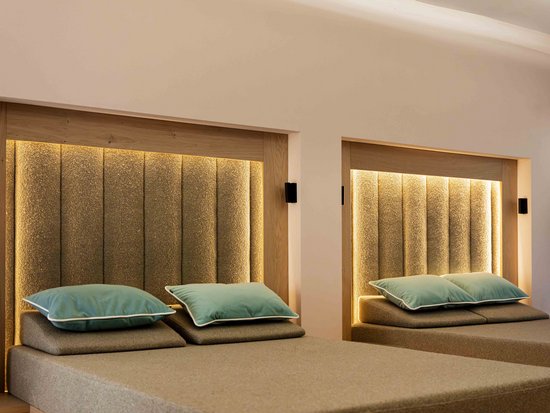 Pool & Sauna Zwei moderne beige Betten mit beleuchteten Kopfenden und blauen Kissen